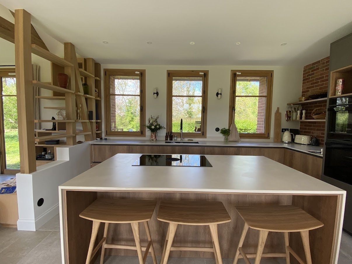 Grande cuisine familiale avec îlot blanc et charpente bois